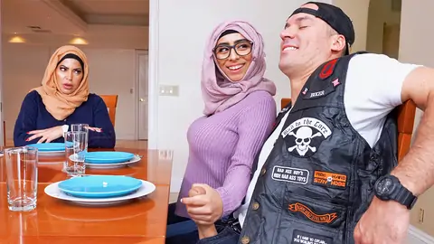 Hijab-wearing woman providing a hand job from under the table